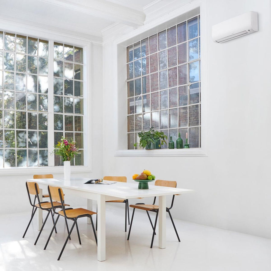 Daikin Comfora binnenunit hoog aan de muur bij een grote raampartij