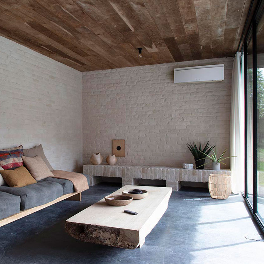Daikin Emura binnenunit in een woonkamer met bakstenen muur