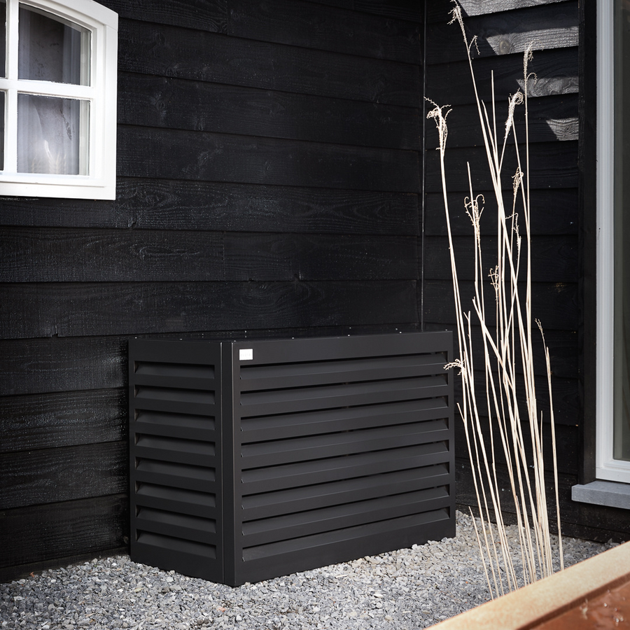Evolar Cover Small in zwart naast een zwarte houten gevel, met siergras